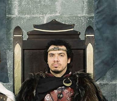 photo du roi Arthur dans Kaamelott, sur son trône, l’air sérieux